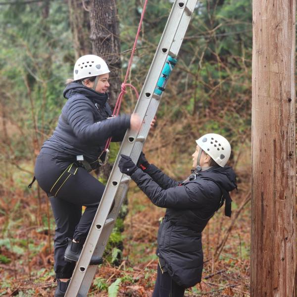 Two CYC students on a ladder in the forest.