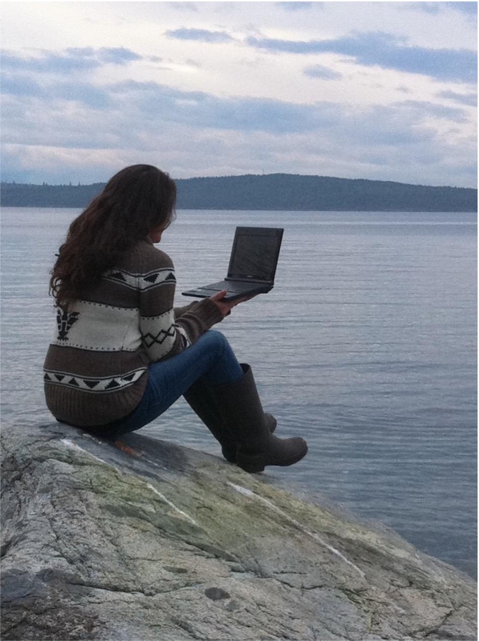 Woman working on a laptop by the ocean